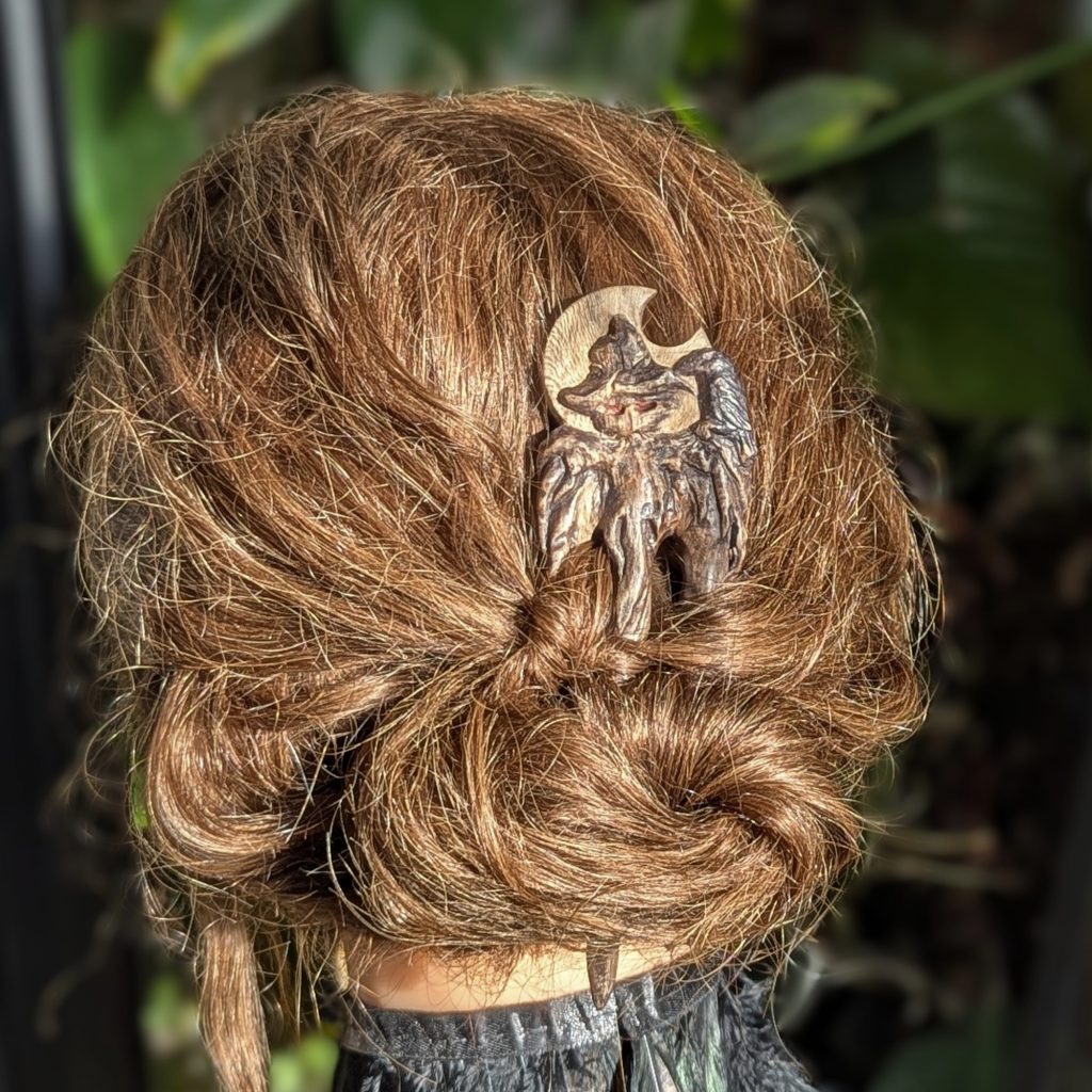 Handgeschnitzte Platanenholz Haarforke „Haunted Best Friend“ mit detailreiner Schnitzerei einer Vogelscheuche und einer Krähe vor einer Mondsichel, ergonomisch gebogen für feines Haar. niedriger dutt